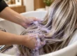 Champú para mechas rubias: peluquera aplicando champú matizador morado en el lavacabezas